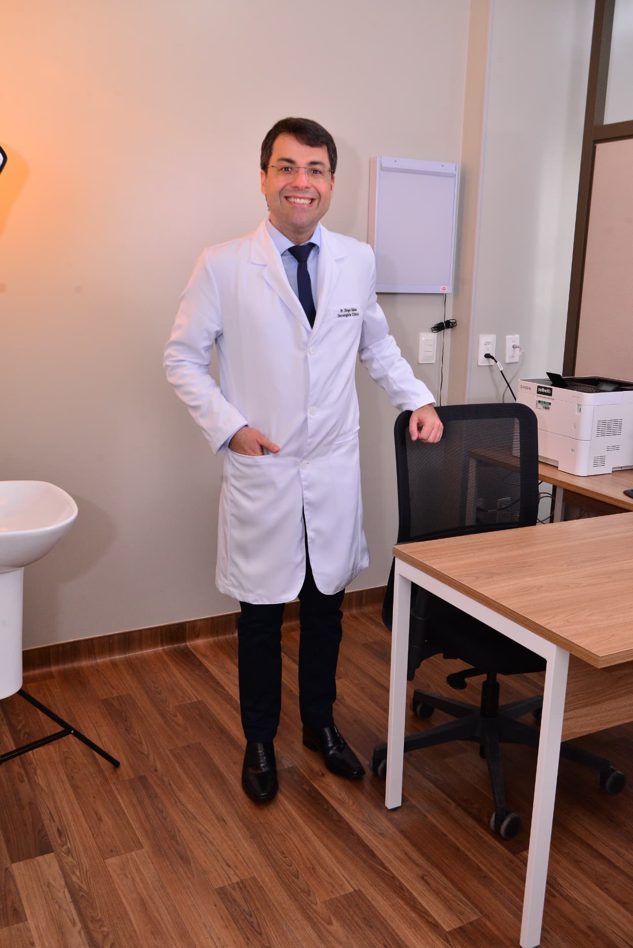 Dr. Diogo Sales em pé no consultório